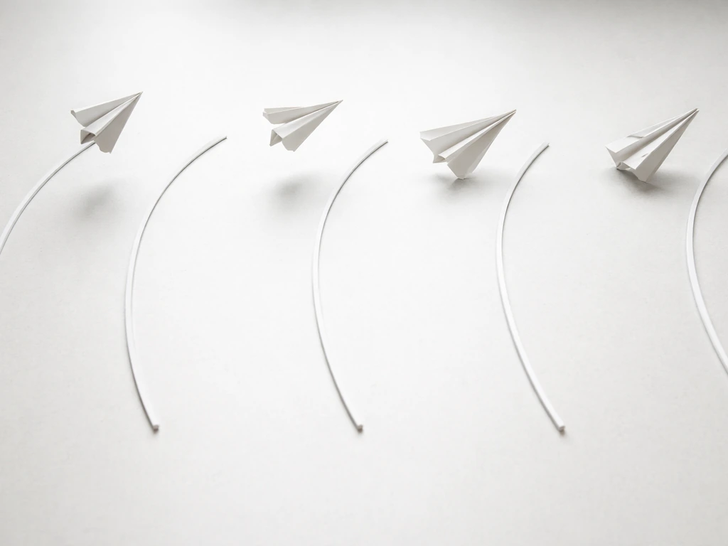 Four-panel photo-style sequence showing a paper bird stabilizing through stall, veer, tumble, and nose-dive fixes.